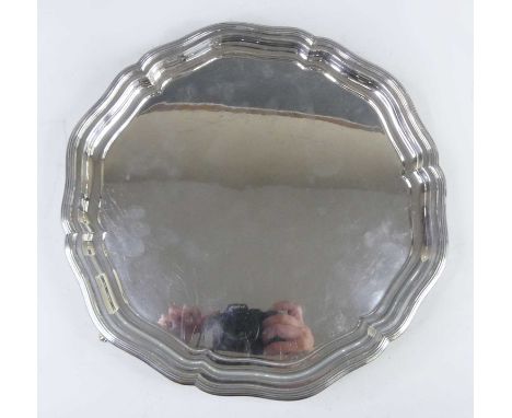 A George IV silver drinks tray, of shaped circular form with raised reeded border, standing upon three outswept reeded scroll