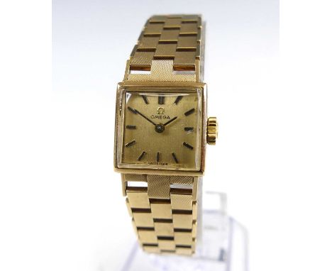 An Omega lady's 9ct gold bracelet watch, having a square champagne dial with baton markers, manual wind movement, on integral