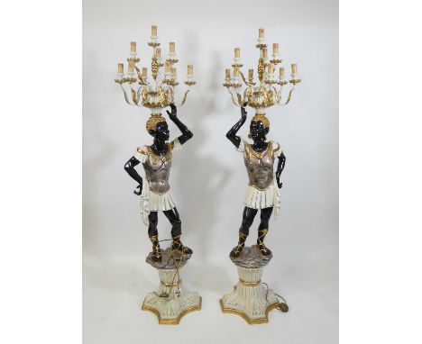 A pair of Victorian style painted composition ten-light 'Blackamoor' figures, each heightened in gilt and raised upon shaped 