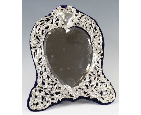 An Edwardian Art Nouveau silver clad easel dressing table mirror, having a heart shaped mirrorplate within a foliate scrollin