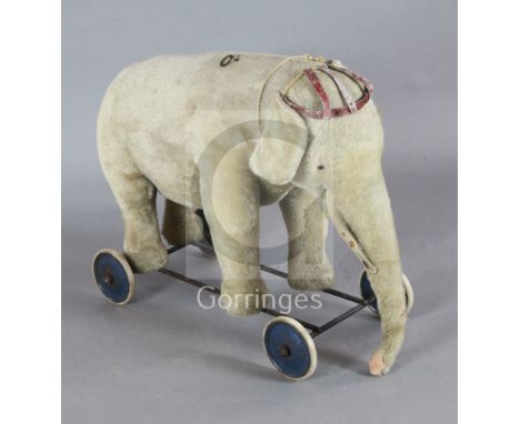A Steiff pale gold plush pull along elephant, with spoke wheels, button to ear, length 29in.