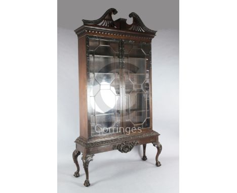 A Chippendale revival mahogany bookcase, with pierced swans neck pediment and floral carved astragal glazed doors, on stand w