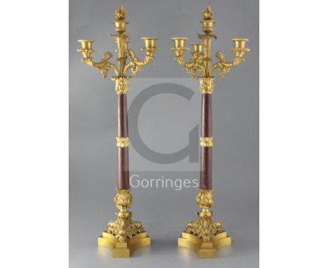 A pair of 19th century, second quarter, French, ormolu and rouge marble four light candelabra, each raised on a stepped base 