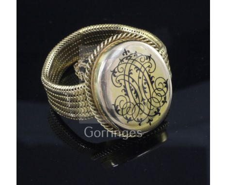 A Victorian gold mesh link and black enamel mourning bracelet with central oval hinged compartment, opening to reveal a minia