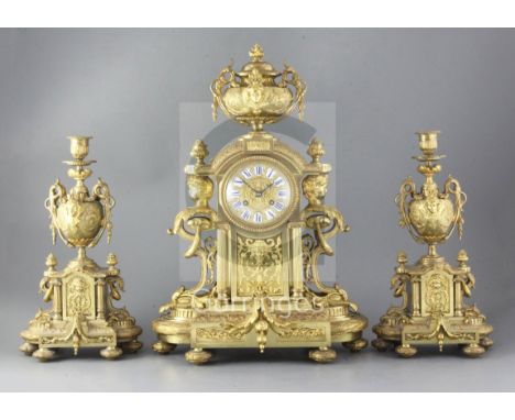 A 19th century French ormolu clock garniture, the architectural break arch case with applied foliate and grotesque mounts cen