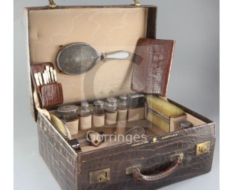 A late Victorian Edwards &amp; Sons crocodile skin travelling toilet case containing assorted silver and tortoiseshell bottle