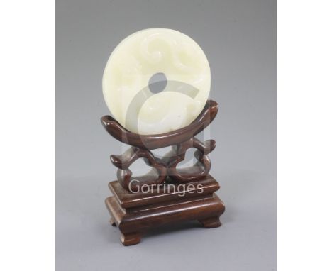 A Chinese white jade bi disc, carved in high relief with a chi-dragon, the underside with taotie masks and scrolls, the stone