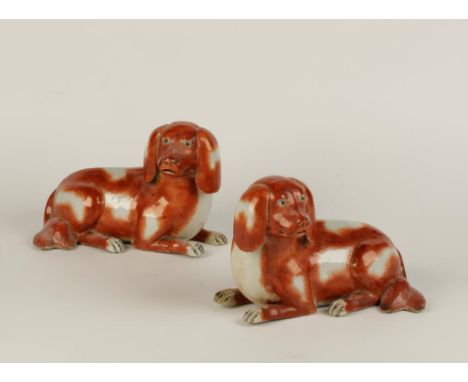 A PAIR OF CHINESE RECUMBENT DOGS, each alert and with iron red patched coat, Qianlong, 9" long