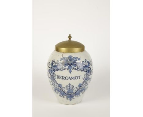 A DELFTWARE TIN GLAZED TOBACCO JAR painted in blue with a floral cartouche "Bergamot", with a brass cover, 18th century, 12.5