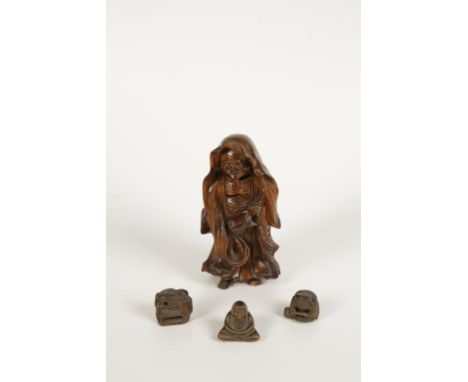 A JAPANESE CARVED WOOD NETSUKE in the form of a man seated wrapped in a cloak, Meiji, 19th century, 1.5" high, and two other 