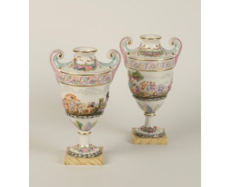 A PAIR OF DOCCIA STYLE ITALIAN PORCELAIN VASES of urn form with polychrome painted classical scenes in relief with scroll han