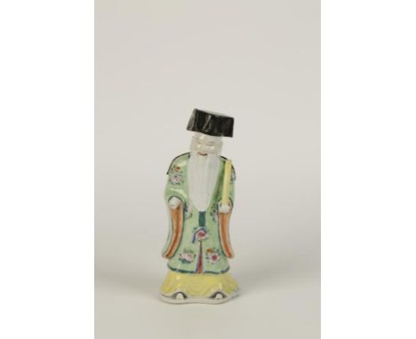 A CHINESE FAMILLE ROSE IMMORTAL standing holding a scroll, wearing a floral sprigged green coat, 9.5" high