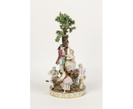 A MEISSEN PORCELAIN CENTREPIECE with figures standing around a rocky base below a tree, polychrome painted and encrusted with