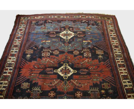 A SHIRVAN SMALL CARPET, the shrouded blue field woven with five star burst medallions in varying reds and blues, within a cre