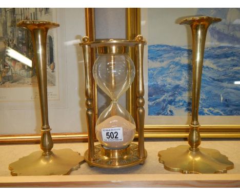 A pair of brass candlesticks and a large brass egg timer