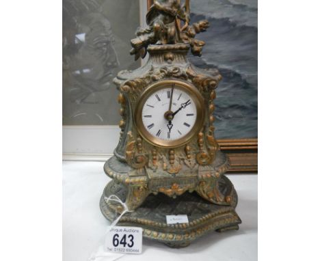 An ornate mantel clock surmounted by a cherub