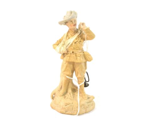 A German Bisque Porcelain Figure of Bugler Dunne, standing, his arm in a sling, a metal bugle raised to his lips, on a rocky 