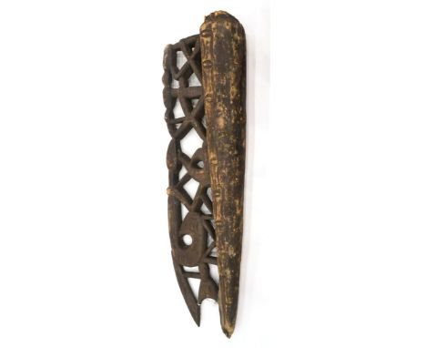 An Asmat Wood Canoe Prow, carved from a single trunk, half of solid rounded form, half pierced and carved with a lattice work