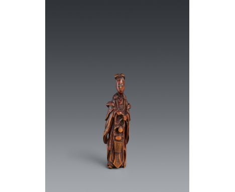 Großes Netsuke der Seiōbō. Buchsbaum. 18. Jh.Die überlange Gestalt hält mit beiden Händen den hohen Henkel eines Korbes mit P