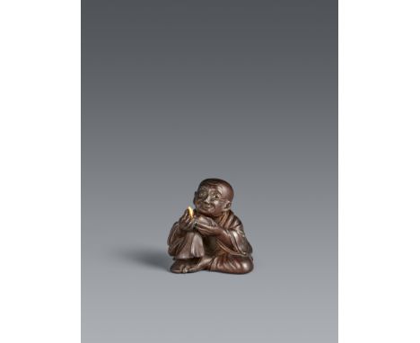 Netsuke eines Tee-Meisters. Holz. Im Stil des Miwa. 1. Hälfte 19. Jh.Mit angewinkeltem Bein sitzend, in der linken Hand ein c