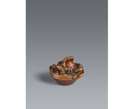 Netsuke eines Kraken in einem Mörser. Buchsbaum. 19. Jh.Sign.: Masatomo kōIn einem flachem suribachi liegt ein Krake, der sei