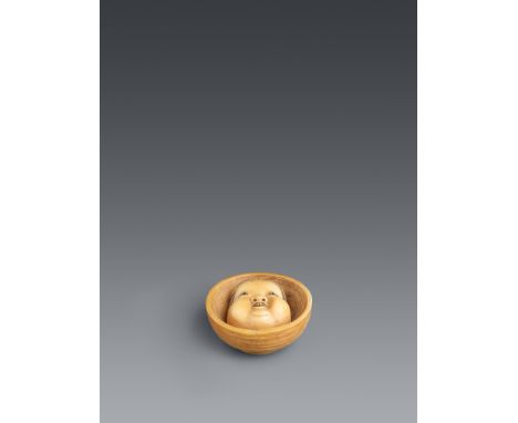 Netsuke einer Otafuku-Maske in einer Schale. Leicht eingefärbtes Elfenbein. Osaka. Mitte 19. Jh.Bez.: MitsuhiroIn einer außen