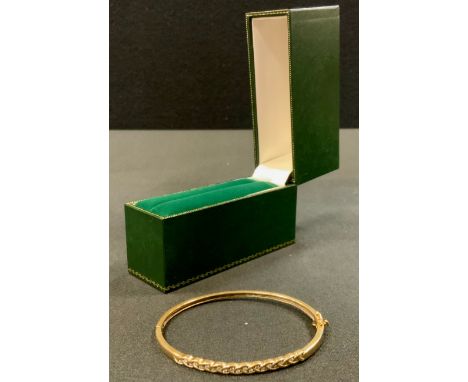 A 9ct gold diamond hinge bangle, over lapping crest inset with twenty two round brilliant cut diamond accents, total estimate