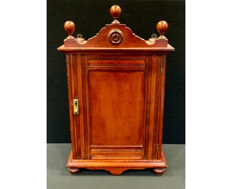 An Edwardian mahogany smokers cabinet, shaped ball pediment, single panel door, fitted interior, shaped frieze, turned bun fe