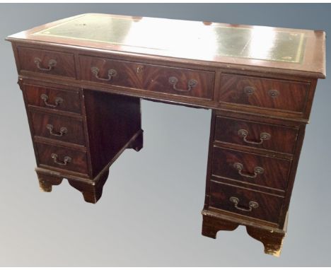 A reproduction mahogany twin pedestal writing desk fitted with nine drawers with green tooled leather panel 