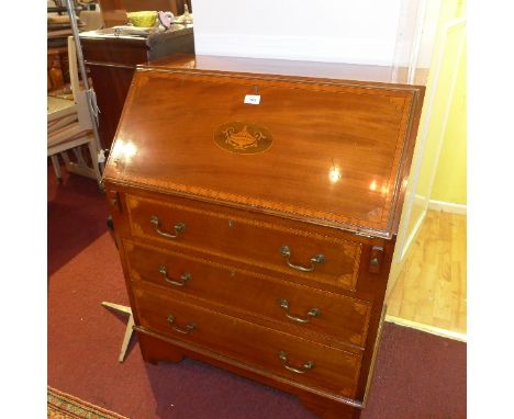 An Edwardian mahogany bureau with drop down flap above three drawers having marquetry inlay raised on carved bracket feet