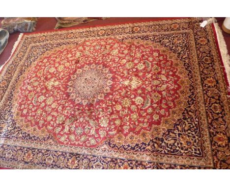 A Keshan style carpet with central floral medallion on a red ground contained by borders. 280x200cm  