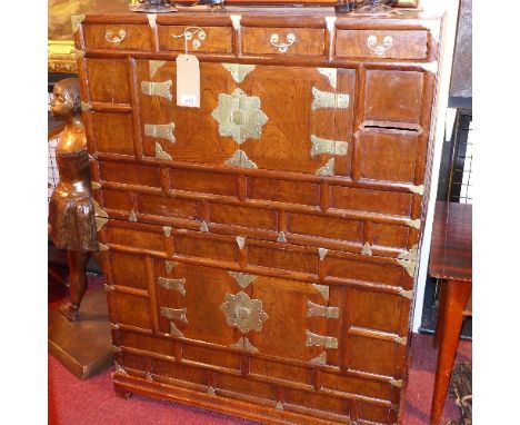 A 20th century Chinese brass bound cabinet, in two sections each having two cupboard doors, raised on stand with bracket feet
