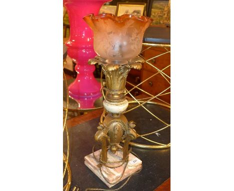 An early 20th Century French table lamp, with floral inlaid red glass shade, above floral neck, raised on tri-form supports, 