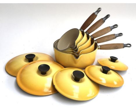 A set of five graduating Le Creuset yellow enamel saucepans, all with lids 