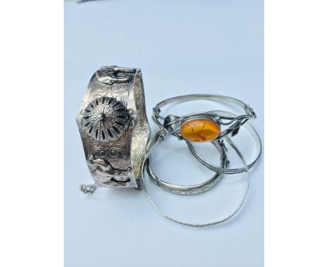 A mixed lot of silver bangles, consisting of one art  nouveau style with an oval amber set to the centre. One hinged bangle w