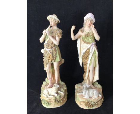 A pair of Royal Dux Bohemia figures modelled as a shepherd playing a pipe with a sheep at his  feet and shepherdess with a go
