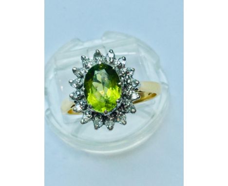 A ladys 18ct yellow gold Peridot and Diamond cluster ring.  The oval peridot measuring 9mm x 6mm is surrounded by 16 x small 