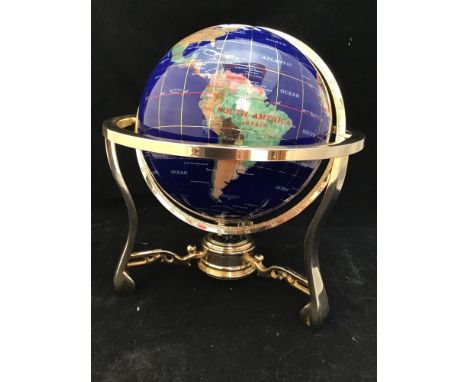 A hard stone globe with inlaid semi-precious stones to blue ground, raised on gilt rotating stand with compass in the centre 