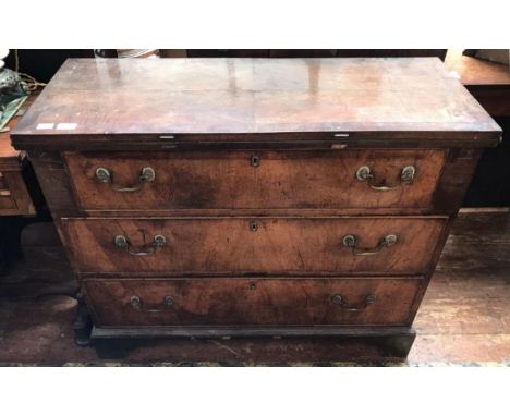 An 18th century walnut veneered chest of three long drawers and hinged and folding rectangular table top with sliding lopers,