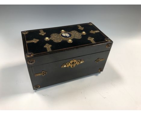 A Victorian ebonised teacaddy, of rectangular form with applied gilt metal decoration, the hinged cover with central enamel p