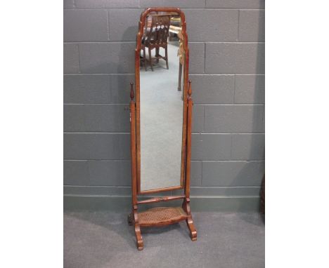 A 1930's walnut framed cheval dressing mirror with canework shelf  