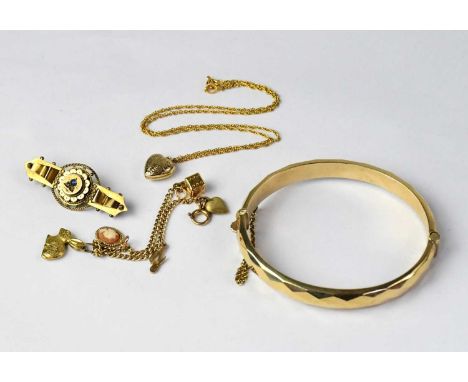 A parcel of 9ct gold jewellery, comprising a bangle, a gem set brooch, a small charm bracelet, and a heart-shaped locket on a