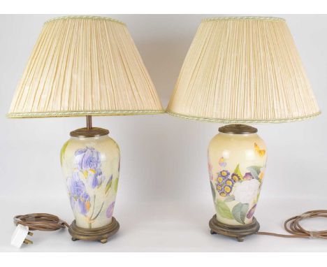 A pair of modern table lamps, the glass bodies of ovoid form, with printed floral design, raised on wooden bases, with shades