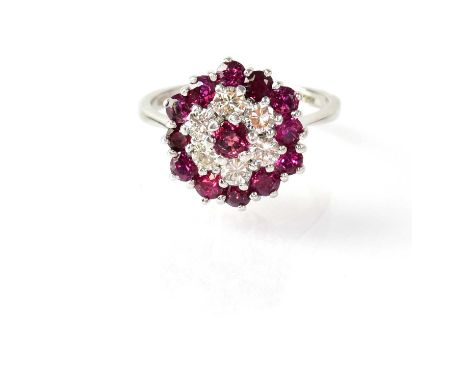 An 18ct white gold cluster ring set with central ruby surrounded by six diamonds, surrounded by twelve rubies, in claw settin