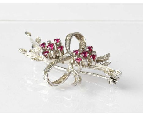 An 18ct white gold diamond and ruby set brooch in the form of a bow, with flower hears and leafy branches, stamped '18CT', le