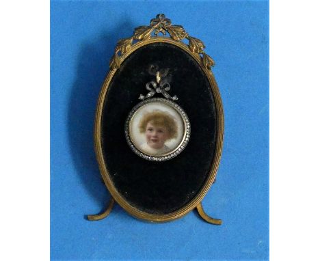 An over-painted photograph portrait miniature, of a child, in gold circular pendant frame inset with seed pearls, the reverse