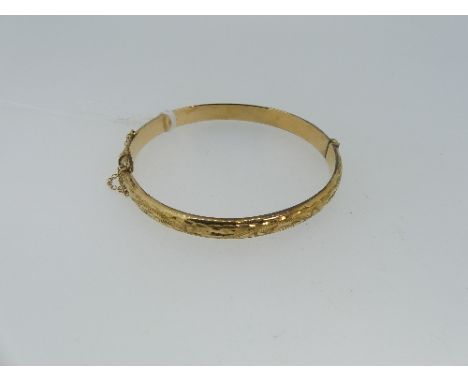 A 9ct yellow gold hollow hinged Bangle, the front with foliate engraved decoration, approx weight 8.5g.