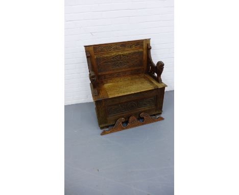 A late 19th century monks oak hall bench having a carved back support and carved arm rest in the form of lions raised on squa