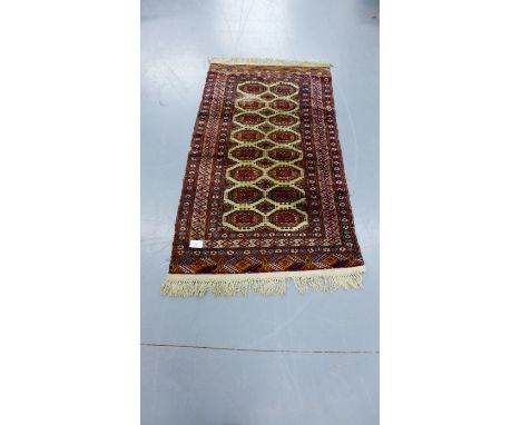 An Afghan style runner the red field with two rows of eight octagons within a multi geometric and floral border, 170 x 96cm