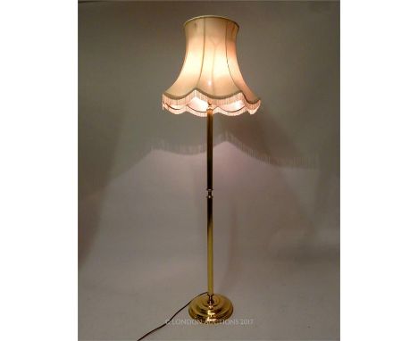 A brass standard lamp with an ivory coloured shade, raised on a circular base, 160 x 50 x 50cm.